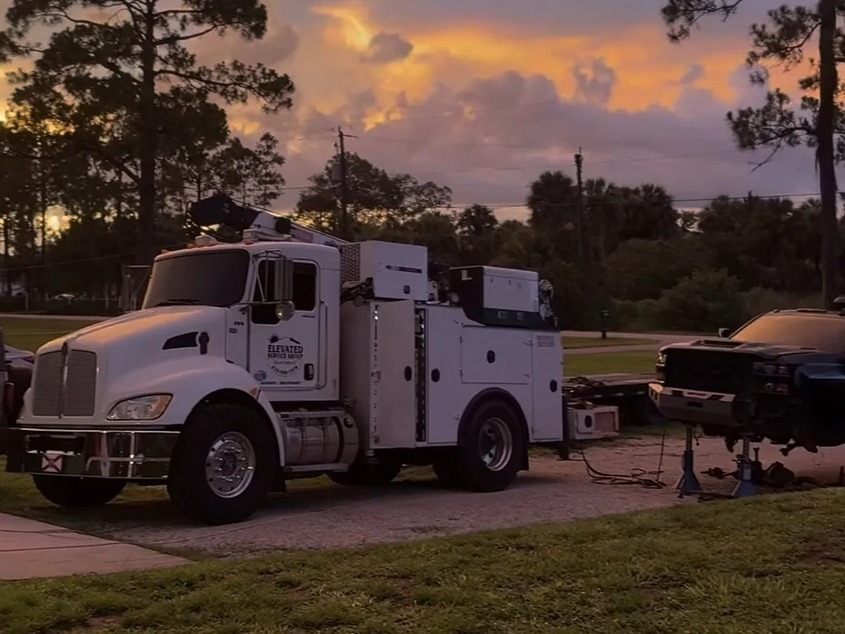 Camión de servicio con grúa de un mecánico de maquinaria pesada, estacionado en un sitio de trabajo en Florida al atardecer